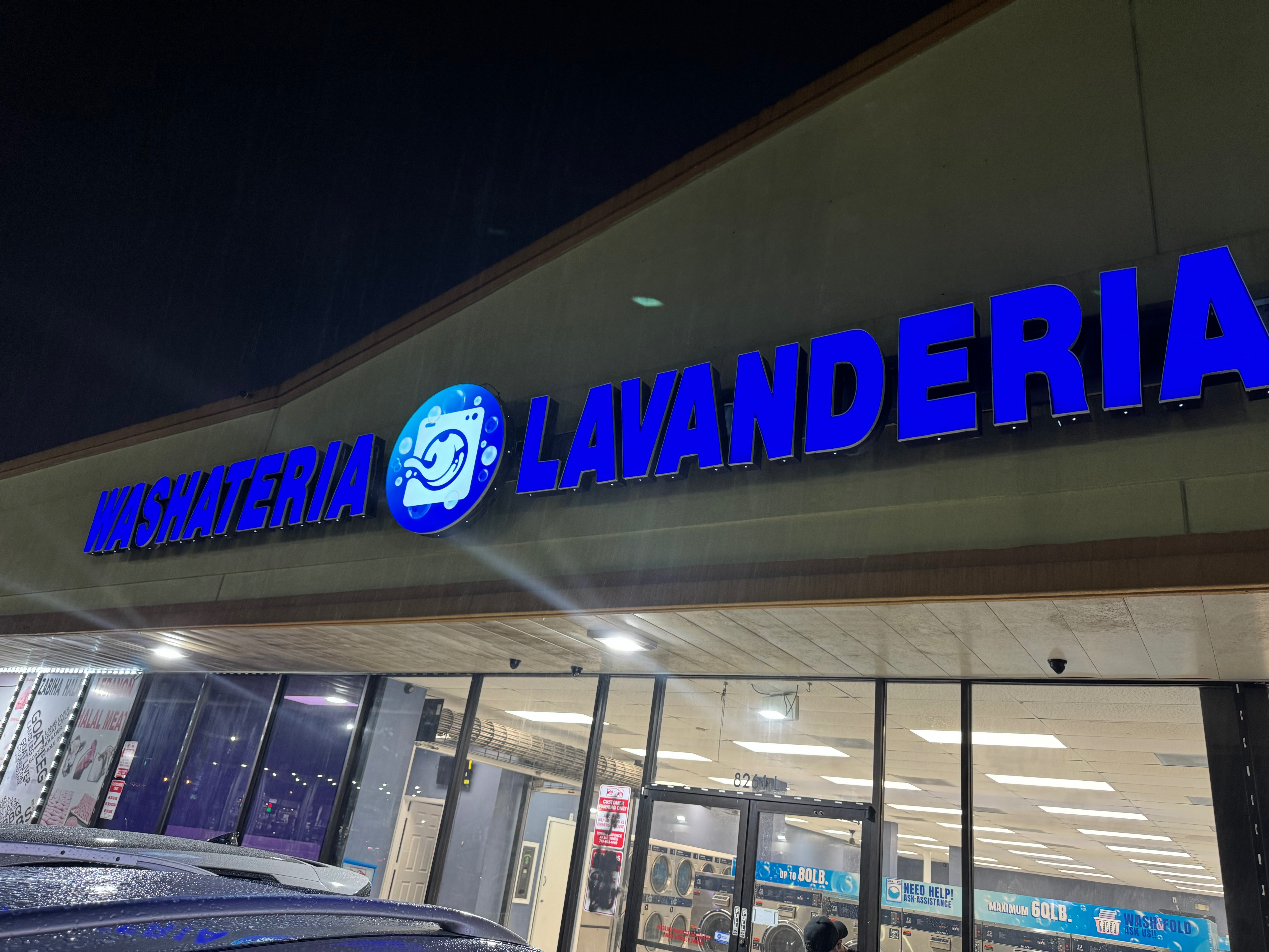 Illuminated Washateria Lavanderia storefront sign at night