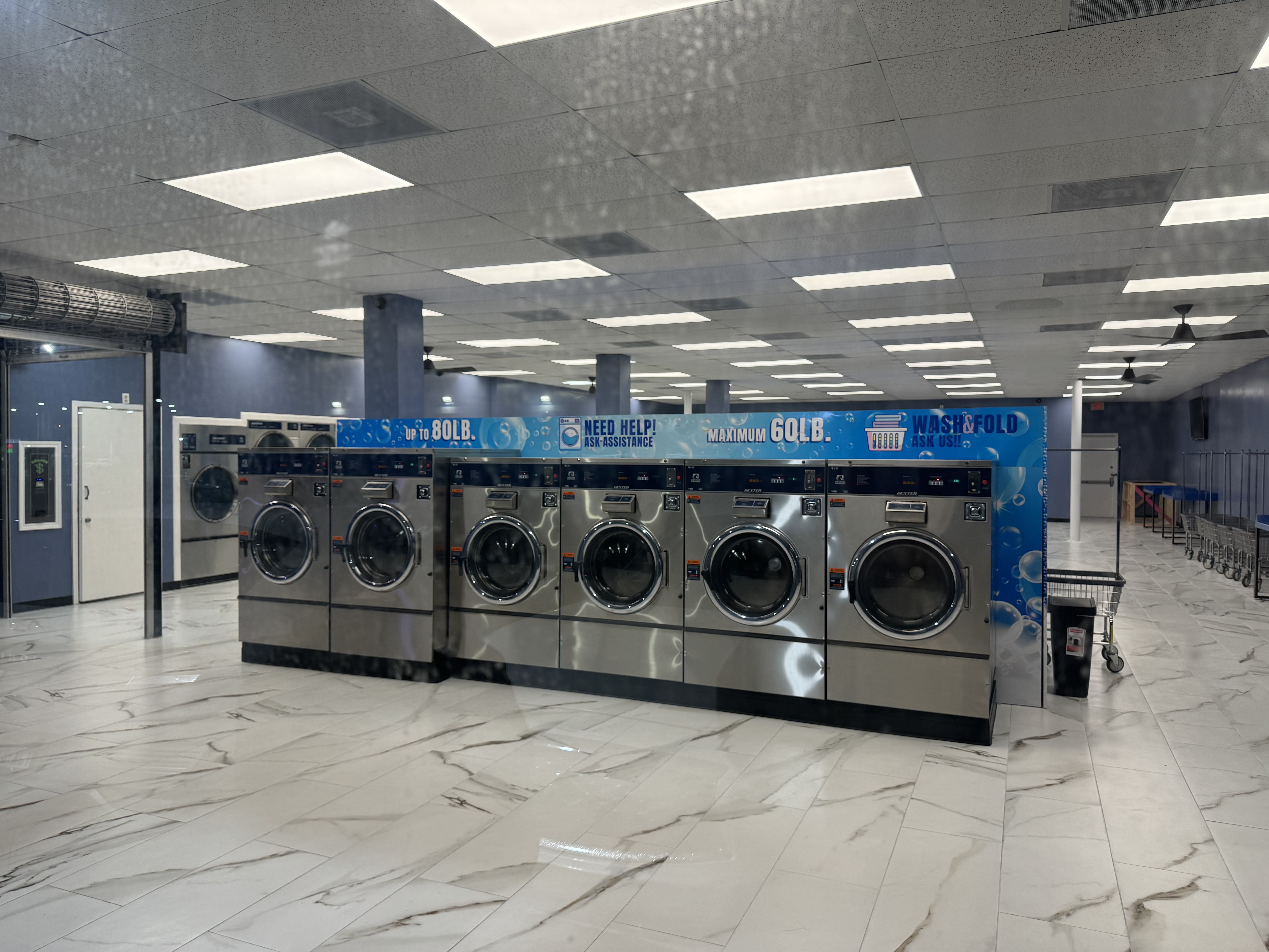 Row of large-capacity washers beside the wash & fold mural